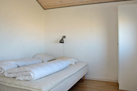 Bedroom with double bed, duvets, and wall lamp in 8 person holiday home in Ulfborg, Denmark.