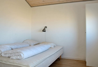 Slaapkamer met dubbel bed, donsdekens en wandlamp in 8-persoons vakantiehuis in Ulfborg, Denemarken.