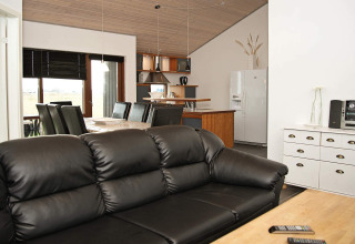 Moderne woon- en eetkamer in een vakantiehuis in Ulfborg, Denemarken, met zwarte lederen zetel en eethoek.