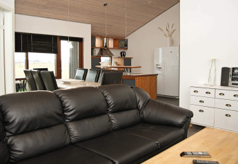 Salon et cuisine modernes dans une maison de vacances à Ulfborg, Danemark, avec canapé en cuir noir et salle à manger.
