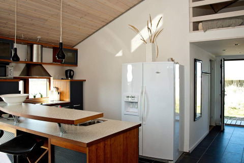 Moderne Küche eines Chalets in Ulfborg, Dänemark, mit weißem Kühlschrank, Frühstücksbar und Holzdecke.
