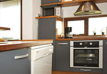 Moderne keuken in een vakantiehuisje in Ulfborg, Denemarken, met oven, vaatwasser en koffiemachine.