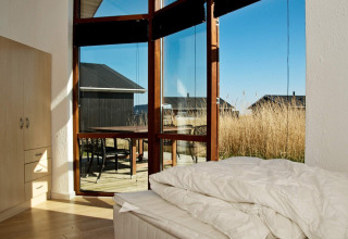 Bedroom with large windows at a holiday home in Ulfborg, Denmark, showing terrace and grass outside.