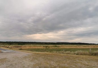 Landschapszicht vanaf het 6-persoons vakantiehuis in Hadsund, Denemarken, onder een bewolkte hemel.