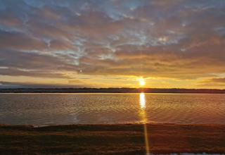 Sonnenuntergang über ruhigem Wasser bei der '6-Personen-Ferienhaus in Hadsund' in Dänemark, mit Wolken.