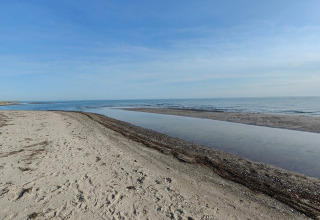Plage de sable et vue sur la mer près de Hadsund, Danemark, sous un ciel bleu clair et paisible.