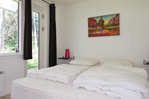 Dormitorio luminoso en casa de vacaciones en Hadsund, Dinamarca, con arte en la pared y vista a la naturaleza.