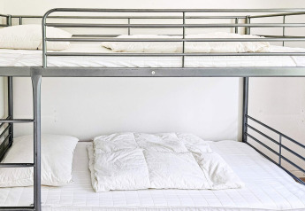 Lit superposé moderne en métal avec draps blancs dans une maison de vacances pour 6 personnes à Hadsund, Danemark.
