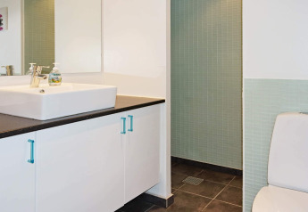 Moderne badkamer in een vakantiehuis in Hadsund, Denemarken met lavabo, spiegel, toilet en douche.