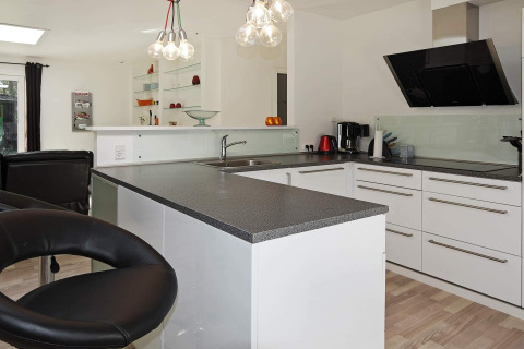 Moderne Küche mit schwarzer Arbeitsplatte und weißen Schränken in einem Ferienhaus in Hadsund, Dänemark.