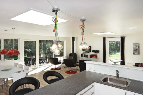 Moderne leefruimte in vakantiehuis in Hadsund, Denemarken, met grote ramen en stijlvolle inrichting.