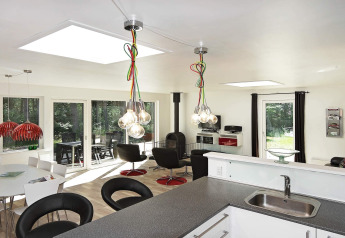 Soggiorno moderno in casa vacanza a Hadsund, Danimarca, con grandi finestre e arredo elegante.