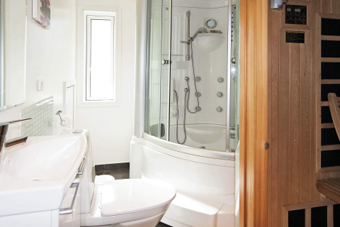 Baño moderno en una casa de vacaciones en Hadsund, Dinamarca, con cabina de ducha y sauna de madera.