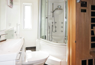 Modern bathroom in a holiday home in Hadsund, Denmark with shower cabin, toilet, and wood sauna.