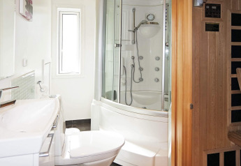 Baño moderno en una casa de vacaciones en Hadsund, Dinamarca, con cabina de ducha y sauna de madera.