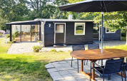 Buitenruimte van 4-persoons vakantiehuis in Allingåbro, Denemarken, met terras, tafel en zwarte gevel.