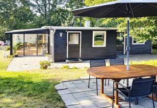 Udendørsområde ved 4-personers feriehus i Allingåbro, Danmark, med terrasse, bord og sort facade.