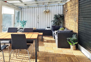 Zonnige veranda in een vakantiehuis voor 4 personen in Allingåbro, Denemarken, met houten vloer en planten.