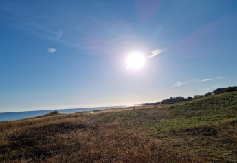 Solrig udsigt over strand og marker ved Allingåbro, fotograferet fra et sommerhus i Danmark.