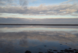 Cielo e nuvole riflessi sull’acqua calma vicino a una casa vacanze per 4 persone ad Allingåbro, Danimarca.