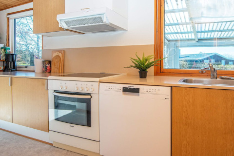 Moderne keuken in een vakantieverblijf in Allingåbro, Denemarken, met oven, vaatwasser en grote ramen.