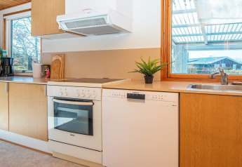 Moderne keuken in een vakantiehuis in Allingåbro, Denemarken, met oven, vaatwasser en grote ramen.