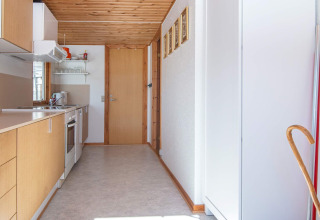 Cocina estrecha y luminosa con gabinetes de madera clara en una casa de vacaciones en Allingåbro, Dinamarca.