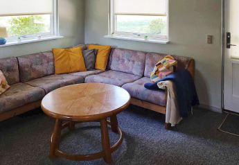 Wohnzimmer in einem Ferienhaus in Allingåbro, Dänemark mit Ecksofa, bunten Kissen und Holztisch