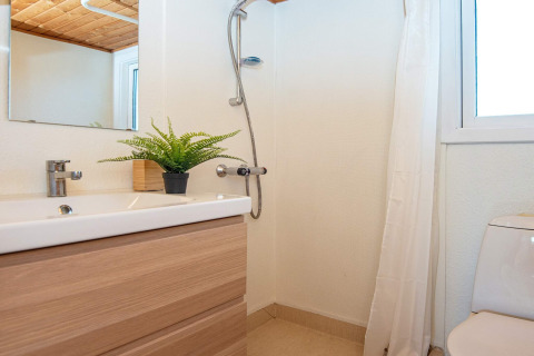 Modernes Badezimmer mit Dusche, Waschbecken, Spiegel, WC und Topfpflanze in einem Ferienhaus in Allingåbro, Dänemark.