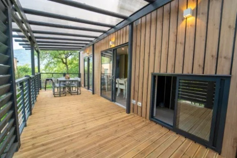 Amplia terraza de madera en Cottage Next XL Superior Dog del Weekend Glamping Resort en Italia, con zona de comedor exterior.
