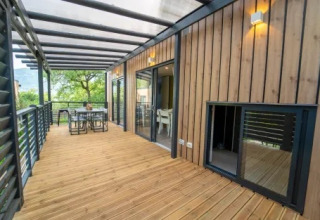 Amplia terraza de madera en Cottage Next XL Superior Dog del Weekend Glamping Resort en Italia, con zona de comedor exterior.