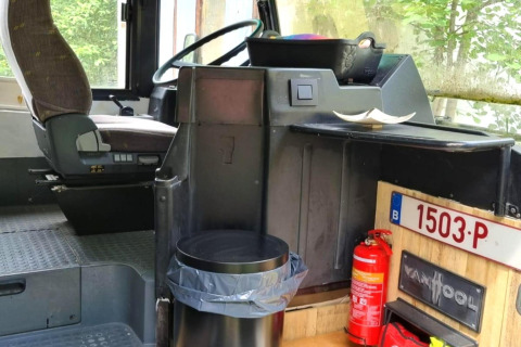 Interiør af mobilhome REEBUS i Belgien med førersæde, skraldespand og brandslukker synlig.
