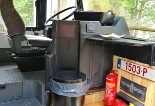 Interiør af mobilhome REEBUS i Belgien med førersæde, skraldespand og brandslukker synlig.
