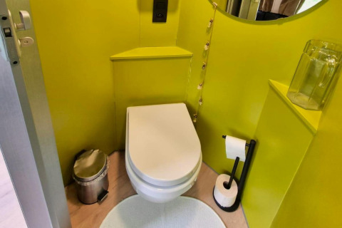 Et moderne mobilhome-toilet ved navn REEBUS i Belgien, med limegrønne vægge, skraldespand og toiletpapir.