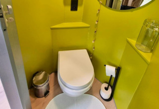 Et moderne mobilhome-toilet ved navn REEBUS i Belgien, med limegrønne vægge, skraldespand og toiletpapir.