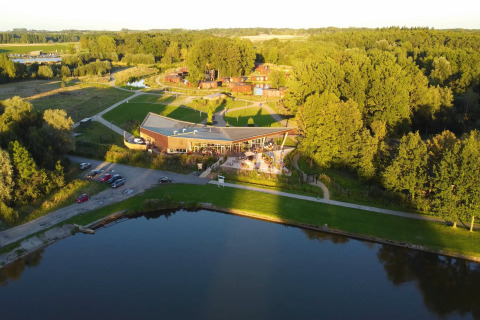 Aerial view of The TreeLoft by YourNature in Belgium, surrounded by forest, water, and open green space.