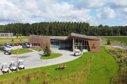 Alojamiento de glamping moderno con grandes ventanales, carritos de golf, estacionamiento y entorno verde.