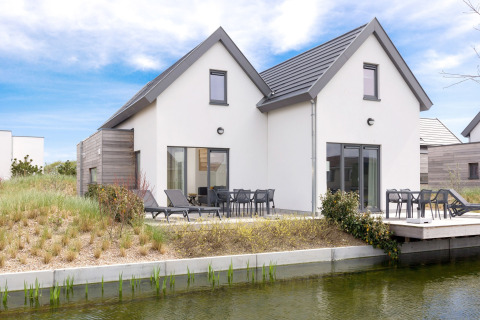Moderne lodge in Breeduyn Village 3, België, met terras, tuinmeubelen en uitzicht op het water.