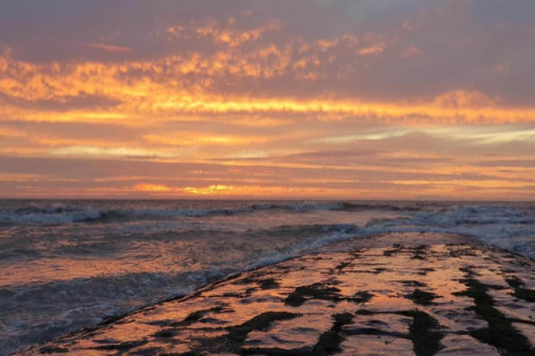 Zonsondergang aan zee bij Breeduyn Village 3 in België, golven en een kleurrijke lucht vol wolken.