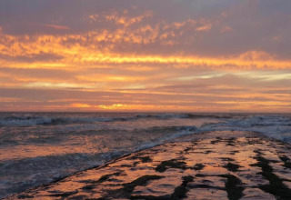 Zonsondergang aan zee bij Breeduyn Village 3 in België, golven en een kleurrijke lucht vol wolken.