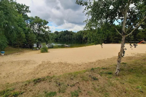 Glampingverblijf met zandstrand, rustige vijver en omliggend bos, perfect om te ontspannen in de natuur.