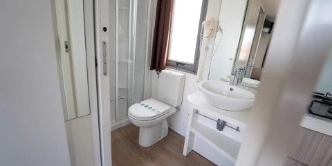 Modern bathroom with toilet, shower, and sink in the Next L Deluxe lodge at Weekend Glamping Resort, Italy.