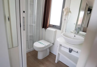 Modern bathroom with toilet, shower, and sink in the Next L Deluxe lodge at Weekend Glamping Resort, Italy.