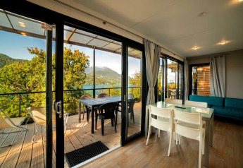 Moderne hytte med panoramaudsigt over sø og bjerge, glasdøre, spisebord og terrasse på Weekend Glamping Resort.