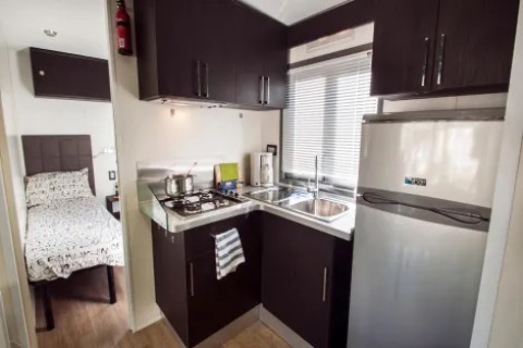 Compact kitchen and bedroom area in Cottage Next XL Superior at Weekend Glamping Resort in Italy.