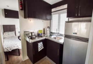 Compact kitchen and bedroom area in Cottage Next XL Superior at Weekend Glamping Resort in Italy.