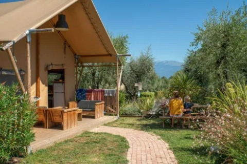 Safari-telt ved Weekend Glamping Resort i Italien med udendørs siddepladser og to personer ved et bord.