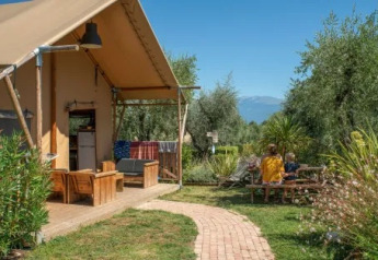 Safari-telt ved Weekend Glamping Resort i Italien med udendørs siddepladser og to personer ved et bord.