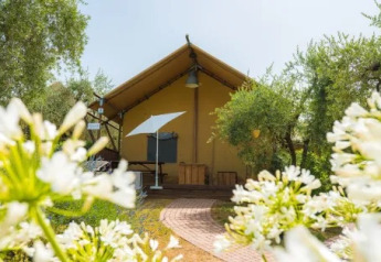 Safari Lodge safari-telt ved Weekend Glamping Resort i Italien, omgivet af blomster og grønne træer.