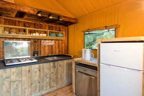Rustikt køkken i Safari Lodge telte med træmøbler, gaskomfur og køleskab på Weekend Glamping Resort i Italien.